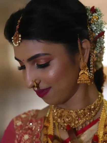 A side profile of Akshatha, highlighting the elegant hairstyle with fresh flowers and the flawless contouring that defines her features.