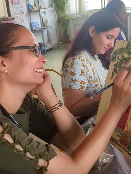 A participant smiling as she paints, fully immersed in the creative process. Our studio is a place for joy and relaxation.