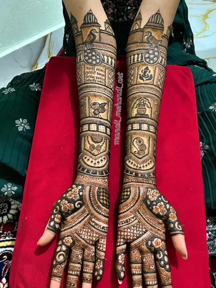 A beautiful example of a traditional full-arm bridal mehandi. The design is packed with classic motifs like Ganesha for blessings, a kalash, peacocks, and intricate jaal (net) patterns for a timeless look.