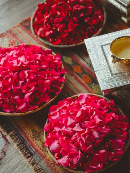 A sunny Haldi ceremony in the British countryside, with details like "Love is all we need" henna, fresh yellow flowers, and bowls of rose petals.