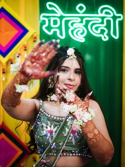 A joyful shot of the bride showing off her henna. The intricate patterns on her arms are a key part of her overall bridal look for the mehndi ceremony.