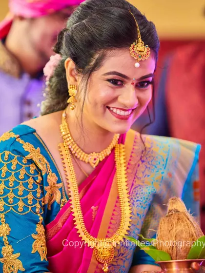The colors in this portrait are stunning. The bride's bright smile, combined with her vibrant saree and gold jewelry, creates a joyful and beautiful image.