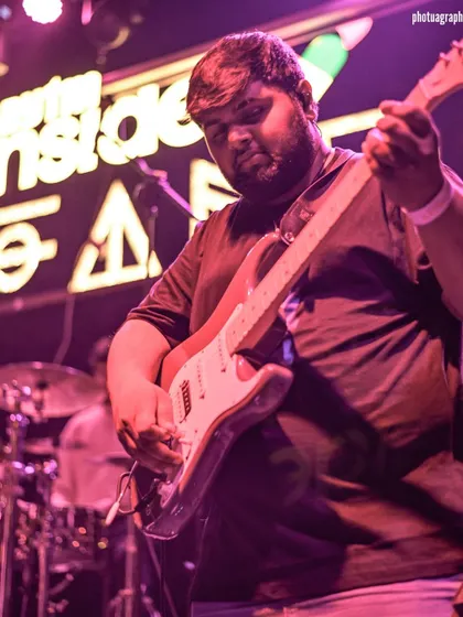 Our lead guitarist, lost in the music under the pink lights of the Fandom stage.