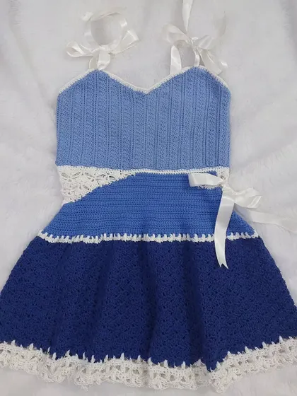 A flat-lay of the Aviva Dress, showcasing the full design with its halter straps and A-line skirt.