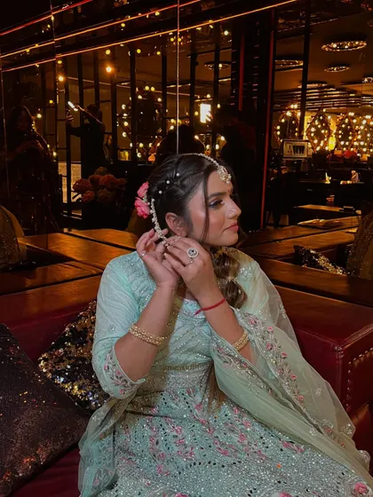 This side view shows the model adding a flower to her hair, highlighting the beautiful braided details and the soft, romantic feel of the hairstyle.