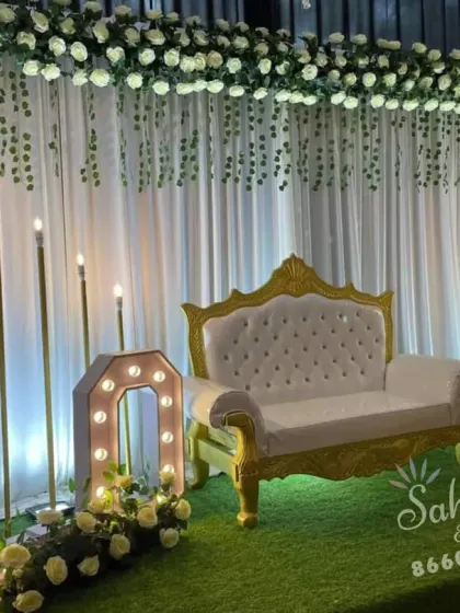 A romantic and elegant anniversary decoration. This setup features a white floral backdrop, an elegant settee, and large "LOVE" marquee letters, creating a perfect ambiance for celebrating a milestone.