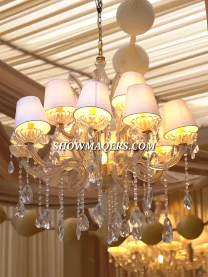 A close up of a beautiful chandelier with lampshades, part of the elegant lighting design for the ivory themed Roka.