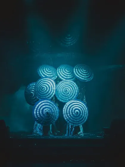 Dancers using hypnotic, spiraling props that glow under the stage lights, adding a surreal and artistic element to the couple's performance.