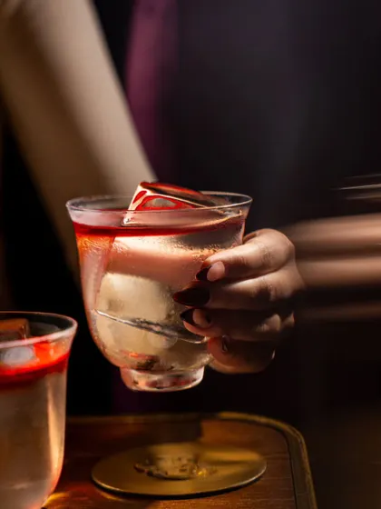 A motion-blur shot of a hand holding a cocktail at Baglami. This technique adds a sense of movement and energy, making the image feel like a captured moment from a lively night out.