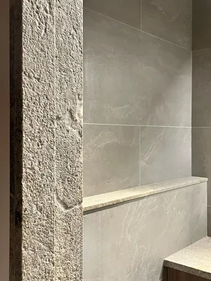 A close-up of a granite pillar at the Polibetta Farmhouse. The rough, hand-finished texture of the stone provides a tactile experience and contrasts with the smooth polished granite used elsewhere.