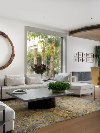 This view of the casual lounge showcases the iconic 'Tango Bar' from our Koko collection, a sculptural brass piece that serves as the room's protagonist. The circular wood installation on the wall adds another layer of organic form, balancing the clean lines of the space.