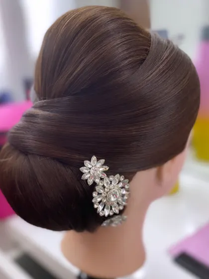 A clean and polished classic bun styled on a mannequin head, adorned with crystal accessories. This demonstrates the foundational technique for creating flawless updos, a key part of my training course.
