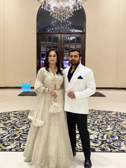 A picture with my husband from my sister's wedding. I wore a beautiful off-white lehenga, and he complemented it with a classic white blazer and black trousers.