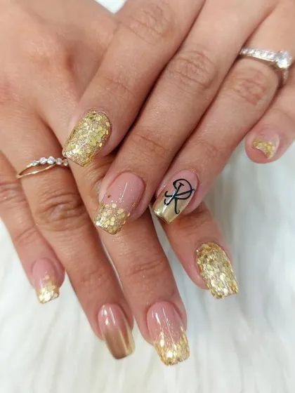 We offer personalized nail art, like adding a custom initial. This celebratory set features a cascade of gold glitter and a beautifully scripted initial, making it perfect for an engagement or anniversary.