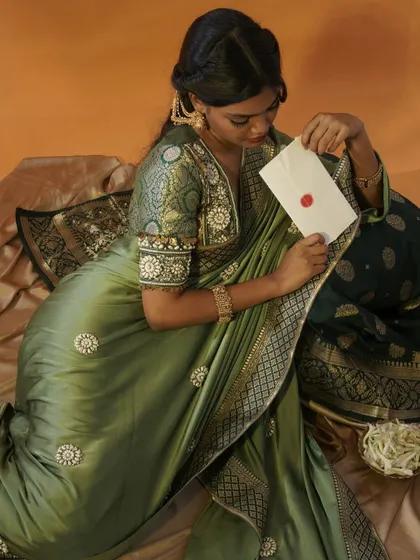 I used a simple prop, a sealed letter, to add a layer of story and intrigue to this portrait. The focus is on the rich fabric of the olive green saree and the model's contemplative mood, creating a timeless, cinematic feel.