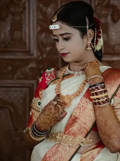 This bride looks elegant and composed for her muhurtham. The makeup is classic South Indian style, with an emphasis on flawless skin, traditional jewellery, and a neat, floral-adorned hairstyle.