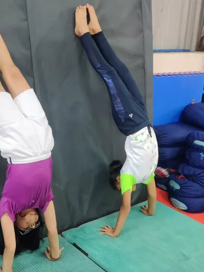 Two students practice their handstands against the wall. This is an essential drill for building shoulder strength and getting comfortable being upside down before attempting freestanding handstands.