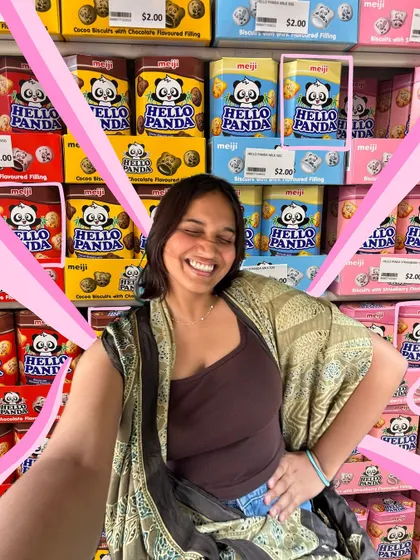 A happy selfie in front of a wall of Hello Panda snacks. The pink doodles add to the fun, joyful energy.