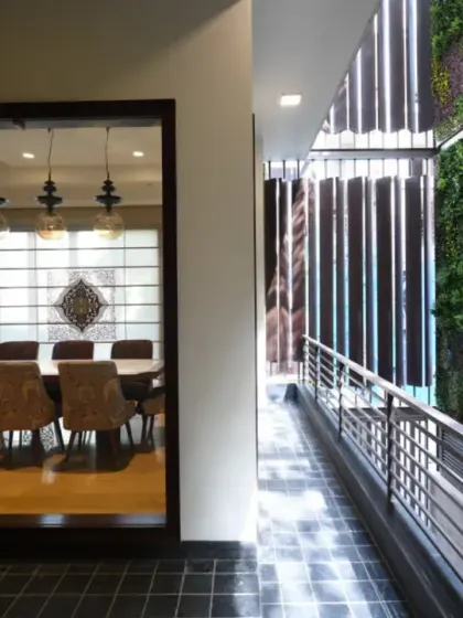 The rear of the Ashraya Residence is screened by metallic louvers and a 40-foot vertical garden wall. A courtyard-like sit-out on the first floor opens up to this lush green backdrop, creating a vibrant and serene outdoor space.