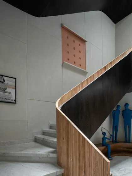 The staircase in The House of Dancing Screens serves as an architectural thread connecting all three floors. Clad in veneer and lit by a skylight, it becomes a sculptural piece that adds elegance to the triple-height space.
