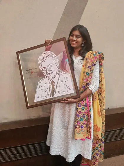 Me holding the finished and framed portrait of Madan Mohan. I added a floral pattern to his suit to give the piece an extra artistic touch.