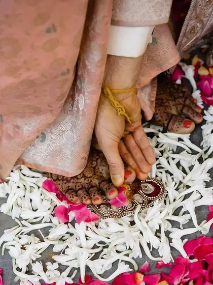 A close up of a traditional ritual involving the couple's feet, surrounded by a bed of flower petals. This detailed shot highlights the beauty and symbolism inherent in Hindu wedding ceremonies.