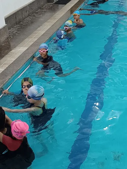A group of kids listening to their coach in the water, showing the interactive and comfortable learning environment I foster.