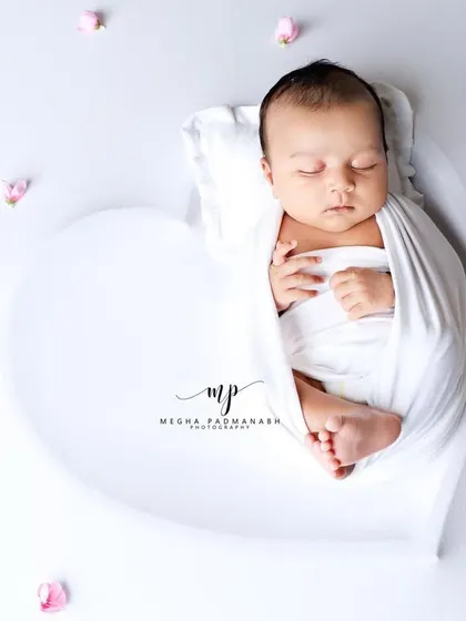 Another angle of the baby in the heart prop with pink petals, creating a soft and dreamy feel.