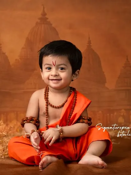 A joyful smile from a young boy dressed as Rama, seated before a temple backdrop. This image captures a happy, relaxed moment during the themed shoot, showing that these sessions are fun for the children too.