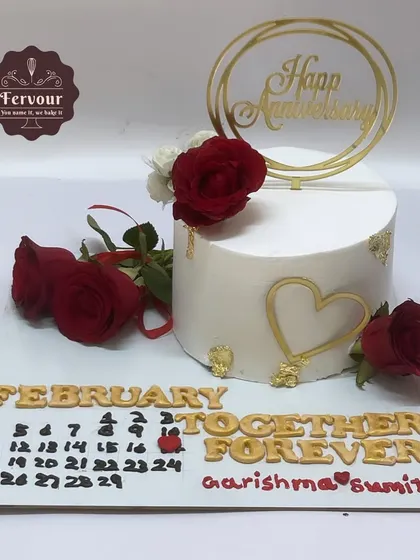 A personalized anniversary cake featuring a calendar to highlight the special date. The design is simple yet meaningful, with fresh red roses adding a touch of classic romance.