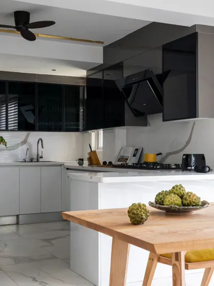 This view shows the dining table adjacent to the kitchen island, creating a fluid space for cooking and socializing. The sleek, handleless cabinetry and integrated appliances maintain a polished, modern aesthetic.