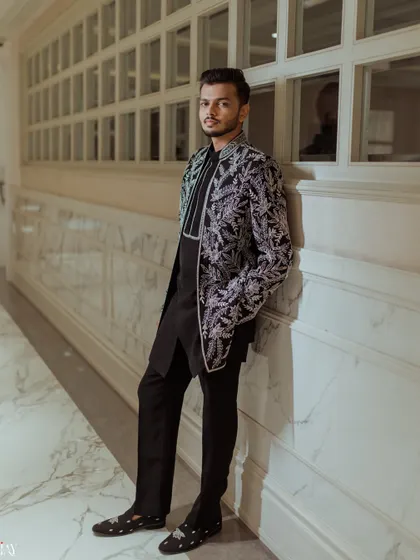A stylish solo portrait of the groom in his black and silver Sangeet outfit.