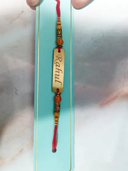A closer look at the craftsmanship of the personalized metal name Rakhi.