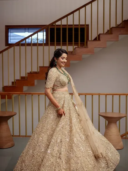 The bride twirls in her golden lehenga, showing the beautiful movement and shimmer of the heavily embellished fabric.