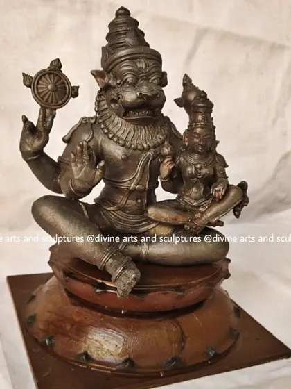 A wax model replica of Lakshmi Narasimha, showing the benevolent form of Lord Vishnu with his consort Goddess Lakshmi seated on his lap. This form represents protection and prosperity combined.