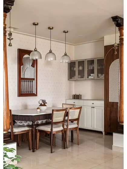 To honor the client's cultural heritage, I designed this dining area with traditional elements like carved wooden columns and a 'katte' bench seat. The dining table features classic leg details, paired with simple cane chairs. A small window mirror on the wall adds depth, reflecting the traditional swing and creating a space rich with history and warmth.