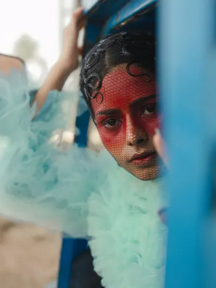 A close-up from the 'Serpent' series, peeking through a blue structure. This framing adds a layer of mystery and focuses on the intense, colorful makeup.