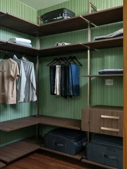 A view of the open-concept walk-in wardrobe, with a modular shelving system set against a textured green wall.