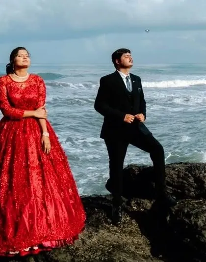 A dramatic pose by the ocean. The groom's classic black suit and the bride's ornate red ball gown, both styled by me, create a powerful and cinematic image.