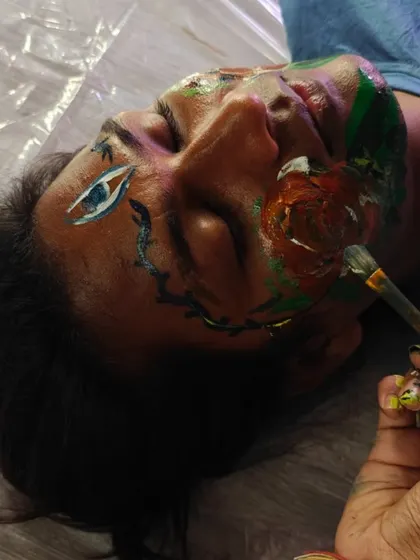 The intimate act of face painting during a workshop. This is a moment of trust and creativity, where one person's face becomes another's canvas. It's a beautiful way to connect.