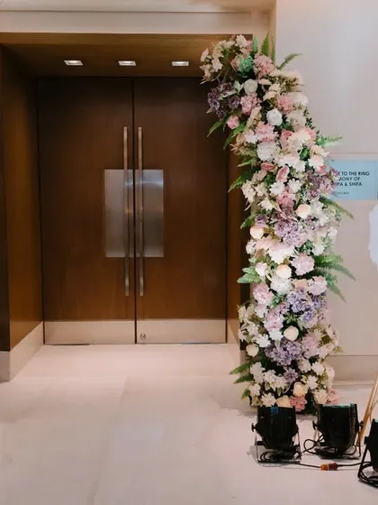 The entrance to the engagement ceremony, featuring a grand floral arch in pastel shades of pink, lavender, and white, creating a soft and romantic welcome.