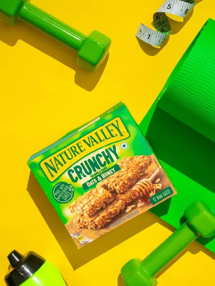 A high-energy flatlay for Nature Valley's crunchy bars. We used a bright yellow background and workout props like dumbbells and a yoga mat to position the snack as the perfect fitness fuel.