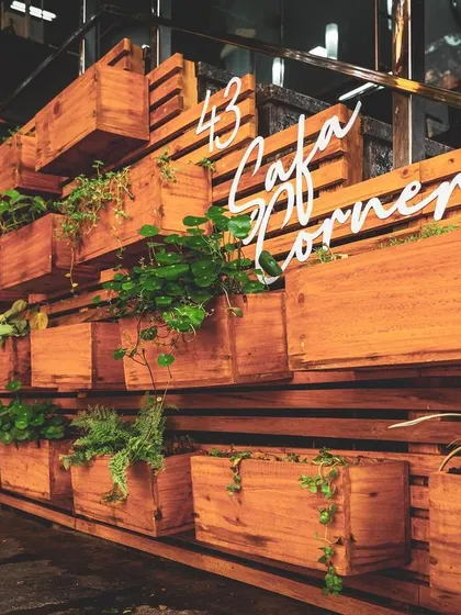 A key feature of the juicery's exterior is this large planter wall made of wooden slats and boxes. It adds a natural, biophilic element that reinforces the brand's focus on fresh ingredients.