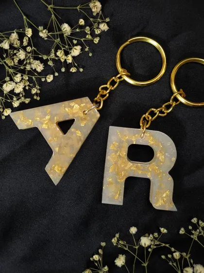 A matching set of 'A' and 'R' keychains in pearl white and gold flake. These are a popular choice for couples or best friends.