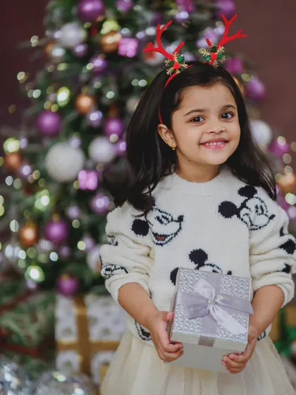 Holding a gift with a bright smile, this little girl is the picture of Christmas joy. We use a variety of props to make our festive sessions interactive and fun for every child.