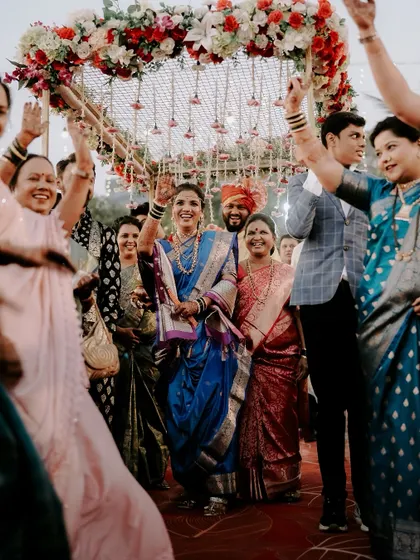 The bride's entrance is pure energy and joy. Here, she is surrounded by smiling family under a beautiful floral canopy. I focus on capturing these high-energy, celebratory moments that define a Maharashtrian wedding procession.
