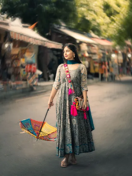 A full-length portrait taken in the vibrant Janpath market in Delhi. I used a 50mm lens to create a beautiful blur in the background, making the subject and her colorful umbrella pop.
