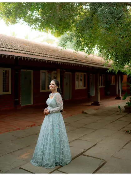 A full-length portrait of Lavanya at her reception, showcasing her elegant gown against the rustic backdrop of the venue.