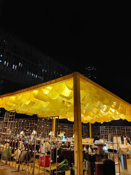 A wider view of the yellow-themed event space, showing the custom canopy with draped fabric against the modern architecture of the building. This highlights our work in transforming outdoor urban spaces.