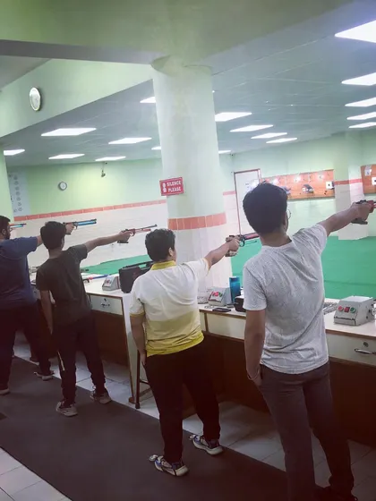 Shooters practicing their 10m air pistol technique, focusing on their stance and arm extension.